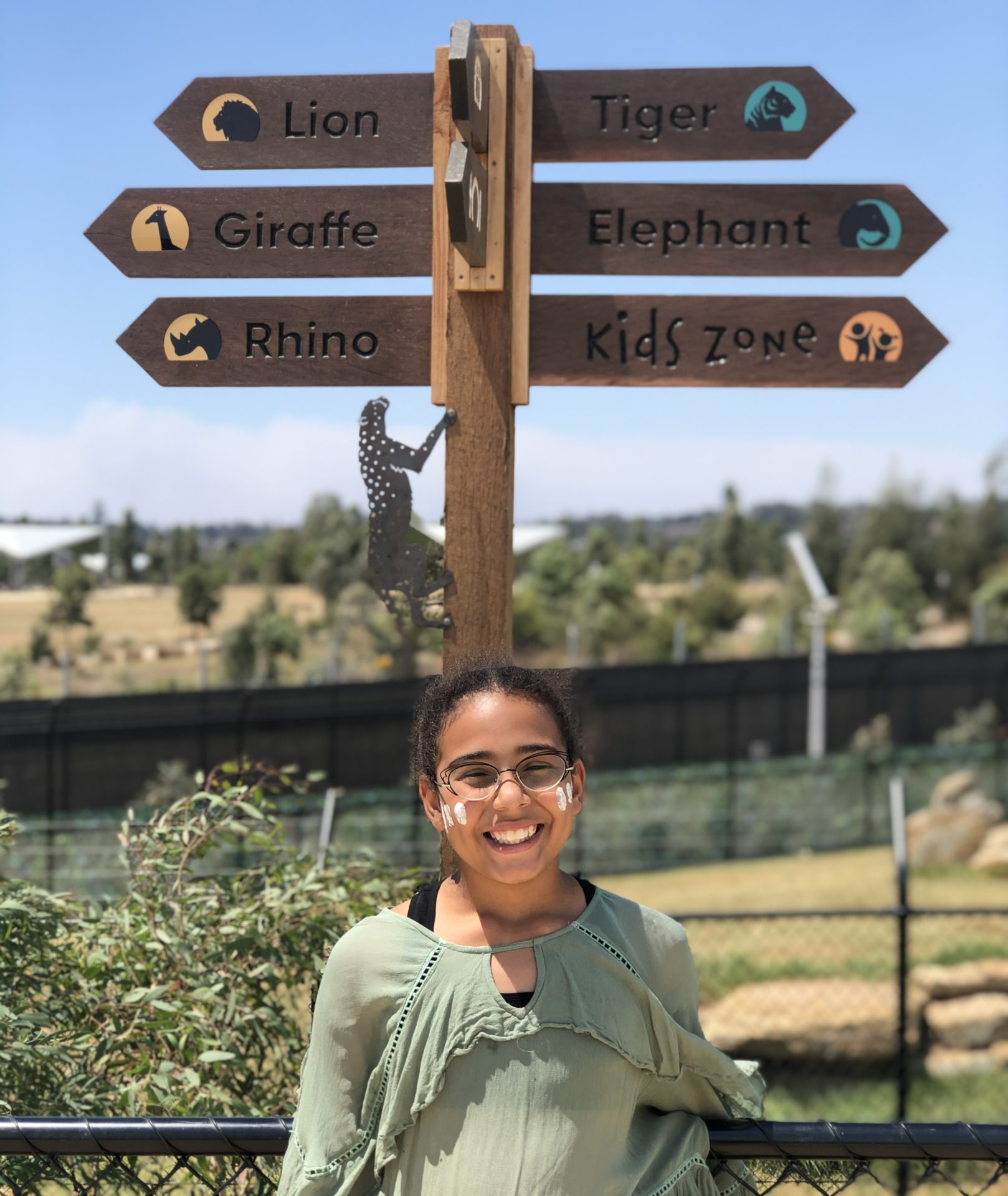 A young girl stands next to a sign post at Sydney Zoo on a school,excursion visit