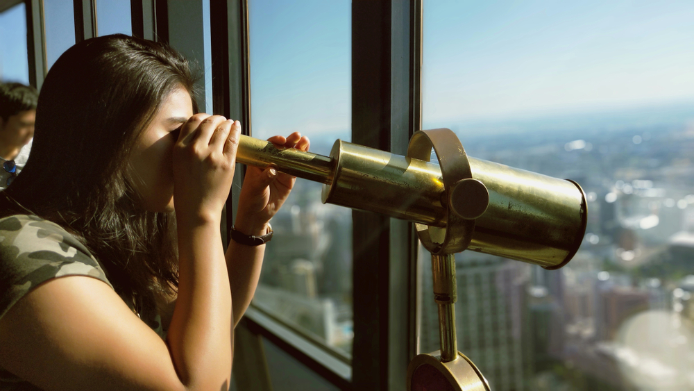 a young last uses a bronze telescope on the sydney tower eye observation deck 